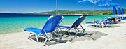 Blå strandstole på sandstrand ved blåt hav